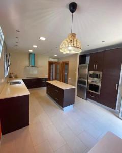 a large kitchen with brown cabinets and a chandelier at Villa Las Palmeras in Tarragona