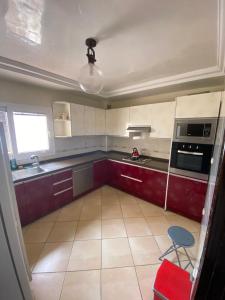 una pequeña cocina con armarios y electrodomésticos rojos y blancos en Appart centre ville, en Agadir