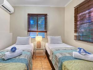 - 2 lits jumeaux dans une chambre avec fenêtre dans l'établissement Picnic Bay Apartments Unit 1, à Picnic Bay