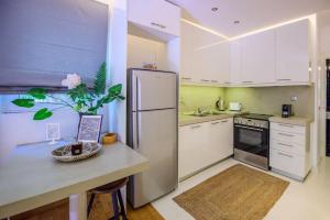 Il comprend une cuisine équipée d'un réfrigérateur et d'un comptoir avec une table. dans l'établissement Seaside 2 BR Boho Minimal Apartment 80m Beachfront, à Athènes