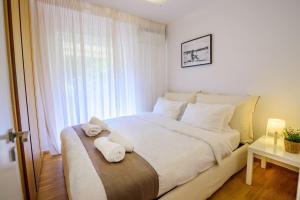 ein Schlafzimmer mit einem großen Bett mit weißer Bettwäsche und Kissen in der Unterkunft Seaside 2 BR Boho Minimal Apartment 80m Beachfront in Athen