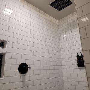 a white tiled shower with a black toilet at The Baker Hotel in Cranbrook