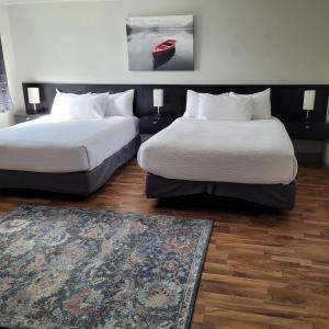 two beds in a hotel room with a rug at The Baker Hotel in Cranbrook