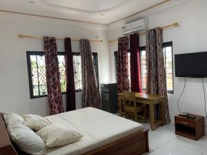 a bedroom with a bed and a television and windows at GUEST HOUSE ILÉ-IFÈ in Ouidah