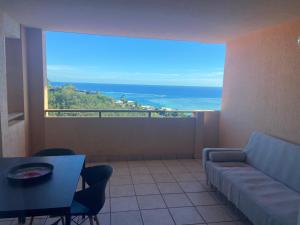 a living room with a couch and a view of the ocean at Punaauia Panoramic View in Punaauia