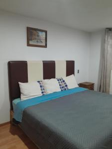 um quarto com uma cama grande e almofadas azuis e brancas em Hotel Posada Doña Maria Esther em Zacatlán