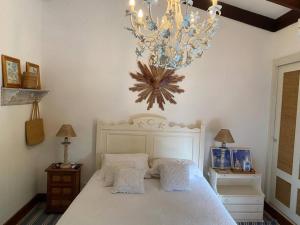 a bedroom with a large white bed with a chandelier at Casa Deliciosa em Condo c/ Piscina Frente ao Mar in São Sebastião +27 photos