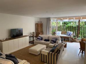 a living room with two couches and a television at Casa Deliciosa em Condo c/ Piscina Frente ao Mar in São Sebastião