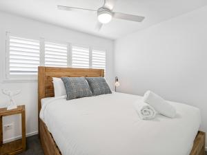 a bedroom with a large white bed with a ceiling fan at Beach City 3 Bedroom Modern Townhouse in Maroochydore