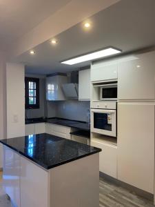 a kitchen with white cabinets and a black counter top at comfortable apartment in an elite area with a beautiful veranda in Port Saplaya
