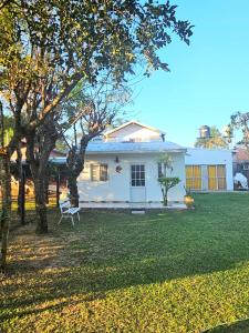 een wit huis met een stoel in een tuin bij La joyita in Ituzaingó