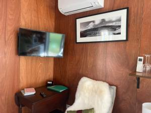 a room with a tv and a chair and a table at Waiora cottage in Otaki