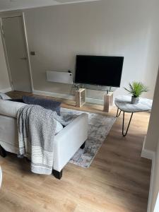 sala de estar con sofá y TV de pantalla plana en TIB Property Investments, Centenary House, 53 North St, en Leeds