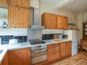 a kitchen with wooden cabinets and stainless steel appliances at Wayside Cottage in Newton-by-the-Sea