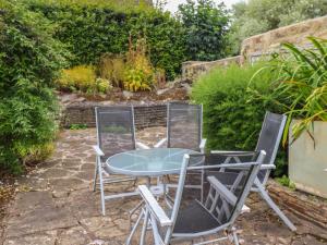 three chairs and a table in a garden at Wayside Cottage in Newton-by-the-Sea