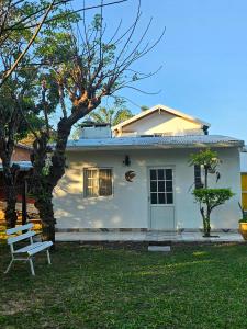 une maison blanche avec un banc dans la cour dans l'établissement La joyita, à Ituzaingó