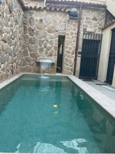 a swimming pool in a stone building with green water at LA CASONA DE BAUTISTA 4 estrellas con piscina montanchez CACERES in Montánchez