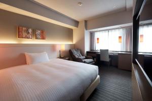 Hotel Forza Oita في أويتا: غرفة في الفندق بسرير وكرسي ومكتب