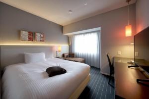 una camera d'albergo con un grande letto bianco e una finestra di Hotel Forza Oita a Oita