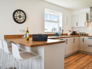 a kitchen with a counter with a clock on the wall at Magnolia Cottage in Appledore