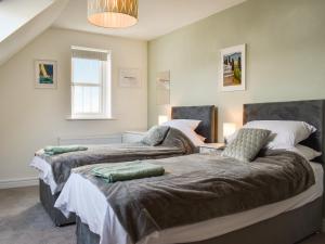 two beds in a room with a window at Magnolia Cottage in Appledore