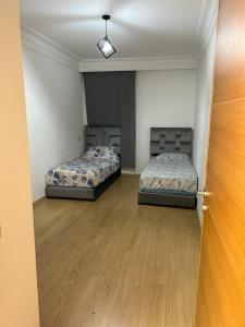 two beds in an empty room with a door at Place Mozart - centre-ville in Tangier