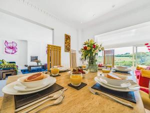 a dining room with a table with plates of food at Pentire in Holbeton