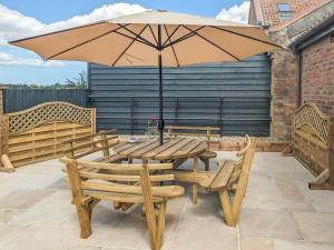 - une table et des chaises en bois avec un parasol sur la terrasse dans l'établissement Hogberts Hideaway, à Carlton Colville