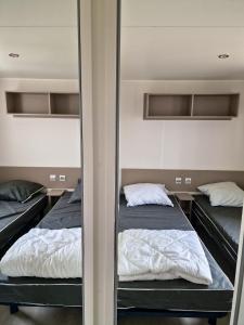 twee bedden in een kamer met een spiegel bij Bungalow de 3 chambres avec piscine partagee et terrasse a Vias a 1 km de la plage in Vias