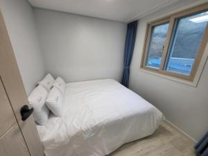 - une chambre avec un lit doté de draps blancs et une fenêtre dans l'établissement Village Pier Pension - Garden, à Yeosu