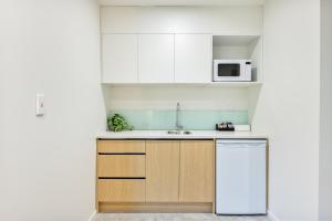 a kitchen with white cabinets and a white refrigerator at Best Western Newmarket Inn & Suites in Auckland