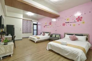 a bedroom with two beds and a pink wall at Wanghong Homestay in Hengchun