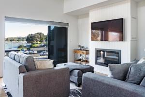 een woonkamer met 2 banken en een tv bij Okiwi Landing in Raglan