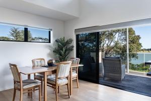 a kitchen and dining room with a table and chairs at Okiwi Landing in Raglan +13 photos