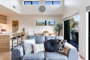 a living room with a blue couch and a kitchen at Okiwi Landing in Raglan