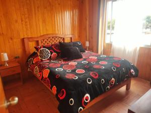 a bedroom with a bed with a black and red comforter at Cabaña2 Punta de Choros in Choros