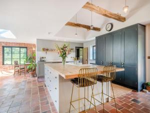 a kitchen with blue cabinets and a counter with stools at Little Orchard in Wood Dalling