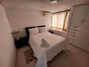 um quarto com uma cama branca com uma toalha em RH05 Riohacha amplio apto mirando al mar 2Hab 4Per em Ríohacha