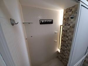 uma casa de banho branca com um chuveiro e um espelho. em RH05 Riohacha amplio apto mirando al mar 2Hab 4Per em Ríohacha