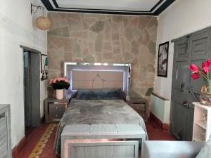 a bedroom with a large bed and a stone wall at Barranca12 in Guanajuato