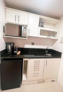 a kitchen with white cabinets and a black counter top at Iguatemi Business & Flat in Salvador