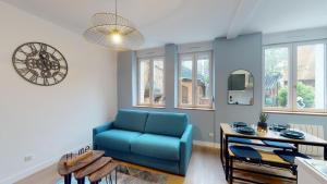 een woonkamer met een blauwe bank en een tafel bij A l'abri du tumulte de la ville in Charleville-Mézières