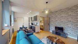 uma sala de estar com um sofá azul e uma parede de tijolos em A l'abri du tumulte de la ville em Charleville-Mézières