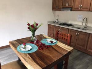 une table en bois avec deux assiettes et un vase de fleurs dans l'établissement Cabaña Luz 2, à Mazamitla