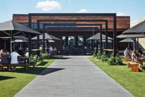 a patio with people sitting at tables and umbrellas at The Golf House at St Andrews Beach in Fingal