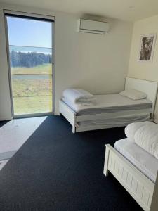 two beds in a room with a large window at The Golf House at St Andrews Beach in Fingal
