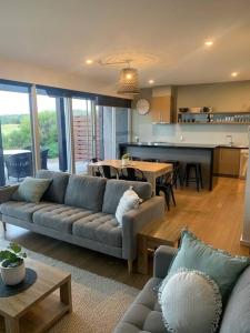 a living room with a couch and a kitchen at The Golf House at St Andrews Beach in Fingal