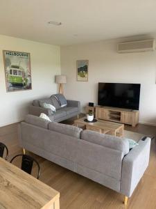 a living room with a gray couch and a tv at The Golf House at St Andrews Beach in Fingal