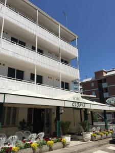 un hotel con mesas y sillas frente a un edificio en Hotel Gloria, en Lignano Sabbiadoro