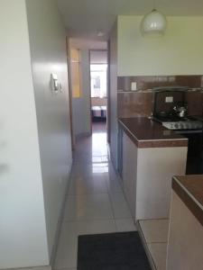 Apart Hotel Costa Verde في تاكنا: مطبخ مع ممر يؤدي إلى غرفة معيشة
